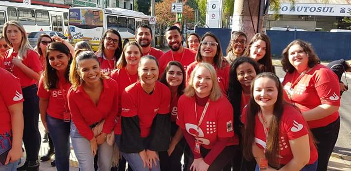 Foto com vários colaboradores Getnet vestindo camiseta vermelha. Evelyn em pé, no canto direito da foto.